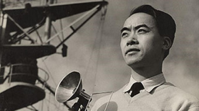 Black and white photograph of Louis Lee, an Asian man, holding a vintage camera.
