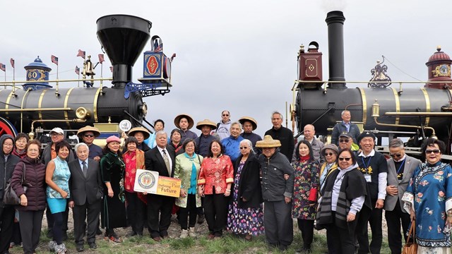 Descendants of the Chinese Railroad workers pose in front of trains. 
