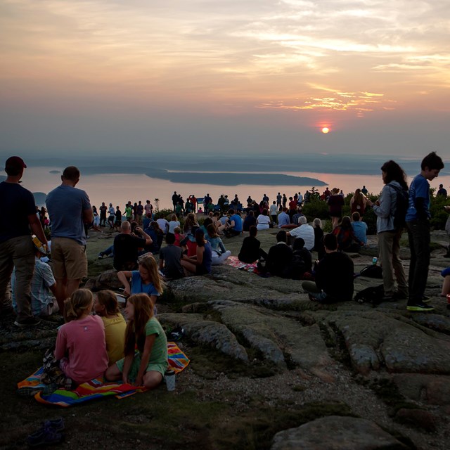 Crowds gather for sunrise on a mountain summit