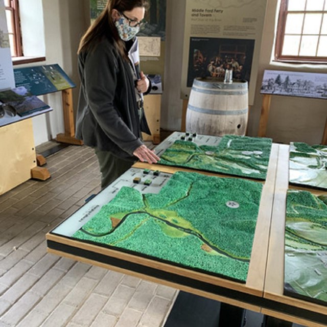 A woman interacting with a large tactile topographical map.