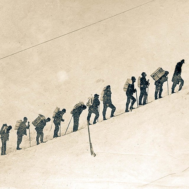 a line of hikers in the snow during the klondike gold rush