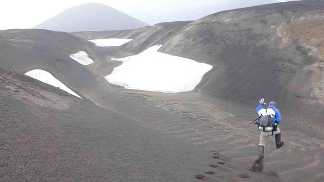 A man jumps along volcanic dunes.