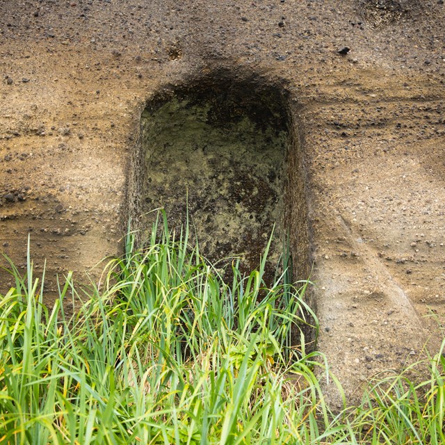 a door-shaped indent in a wall of layered rock.