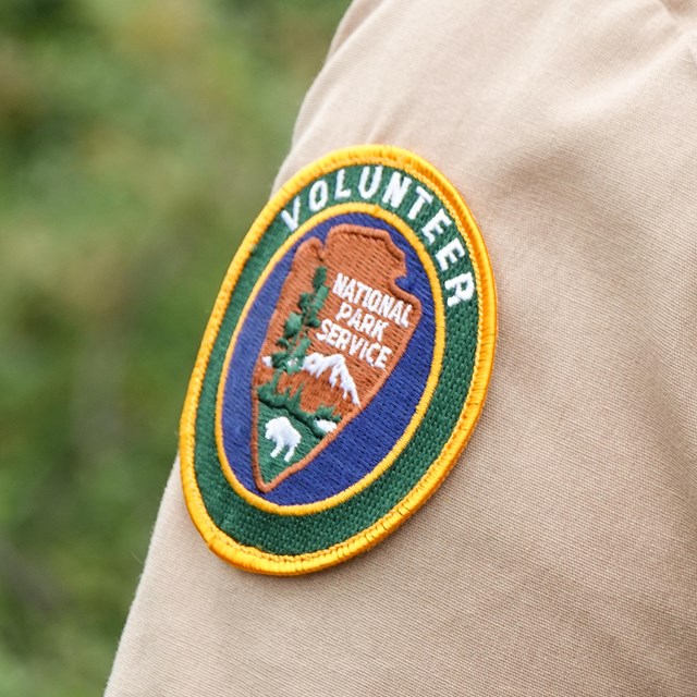 a radio hangs off the backpack of a person wearing a volunteer uniform.