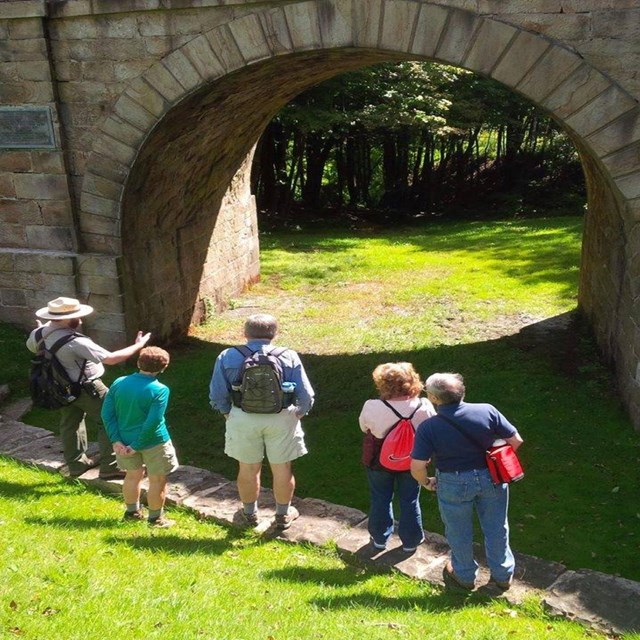 A park ranger talking to a group in front of the Skew Arch Bridge. 