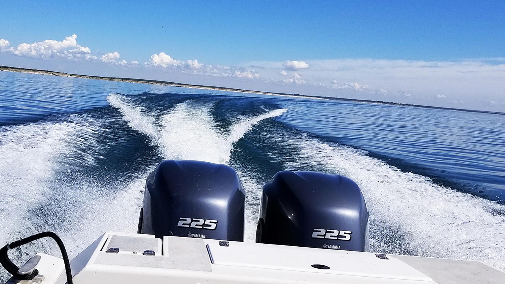 Motorboat stern making a sharp turn and wakes on a still, blue lake
