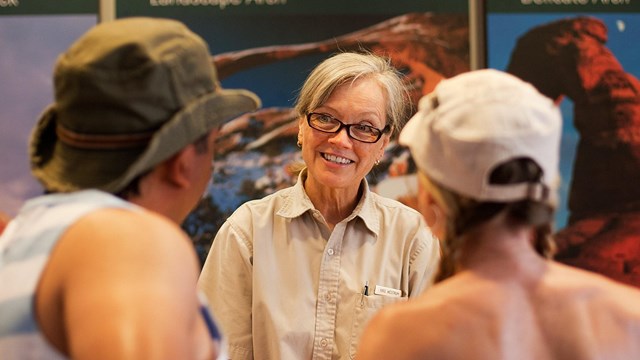 a woman in a brown uniform talks with two people