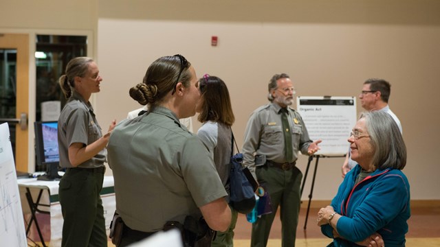 rangers and visitors gather around presentation boards in a meeting room