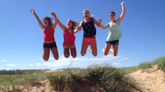 Four kids jumping on a sand dune