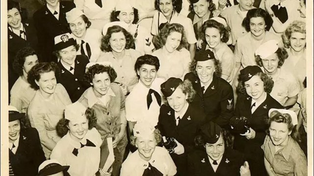 Group photo of several women in uniform smiling up at the camera