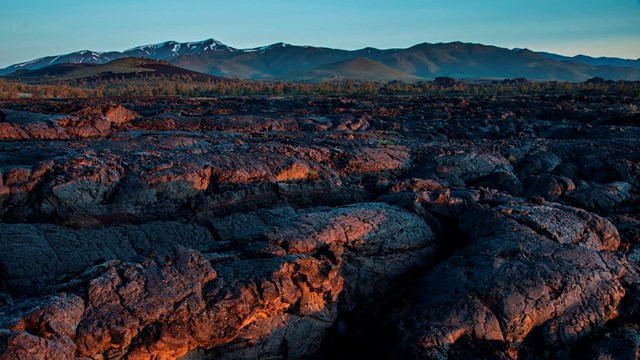 A shot of vast lava flows, with mountains beyond.