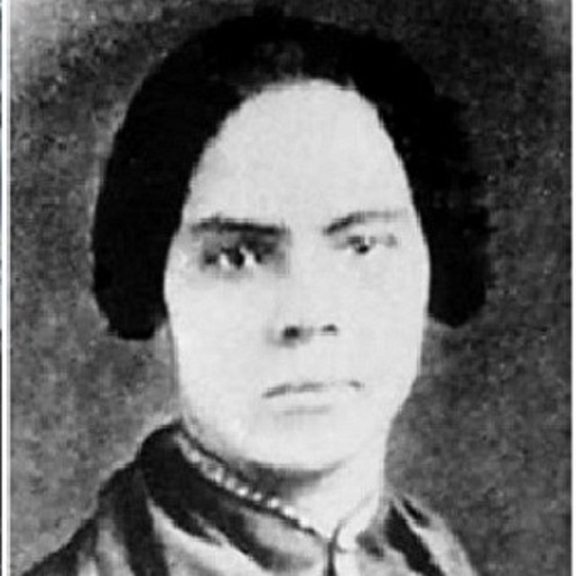 Head and shoulders portrait of a woman wearing a high collar.