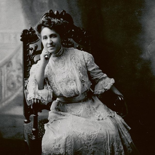 Woman wearing lacy dress sitting in carved chair