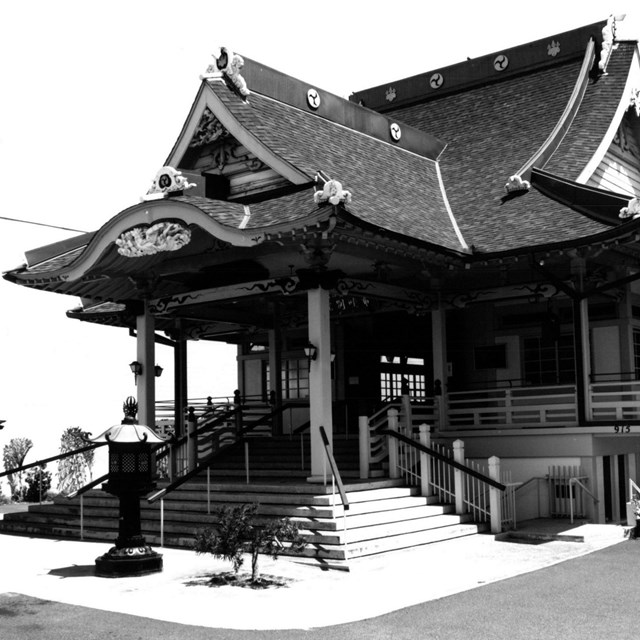 A building with sloped roof, decorative elements, and a large porch and steps in front