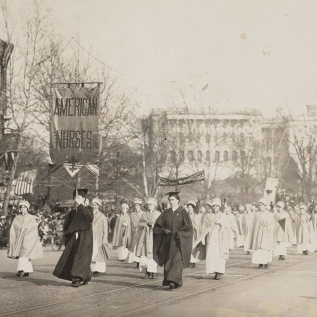 Group of nurses marching in a parade in front of the Capitol