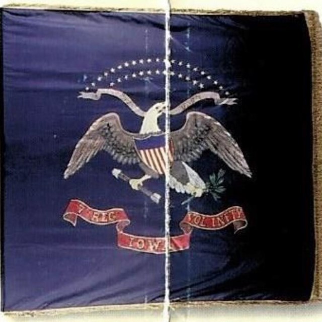 Blue flag with shield and eagle in middle and gold lettering on red scroll