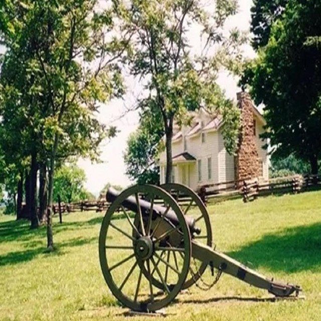 White two story house behind a civil war era cannon.