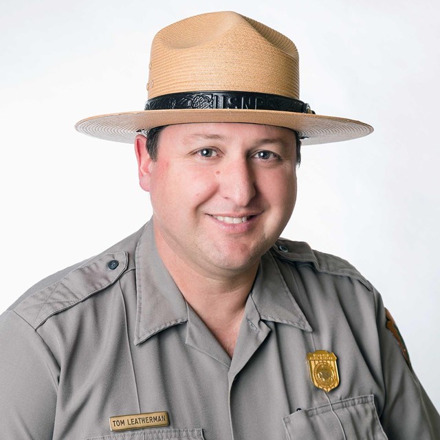 Leatherman wears flathat and NPS uniform and smiles at the camera