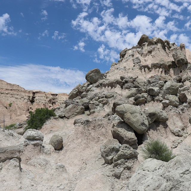 large boulders of rock sit on top of a badlands butte.