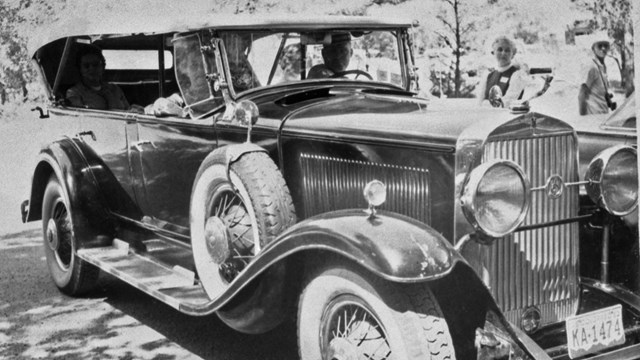 A black and white photograph of an old touring car.