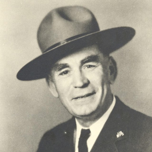 A black and white portrait of a man wearing a park ranger hat.
