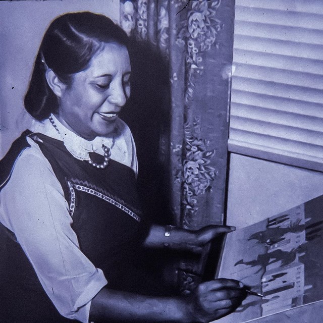 A black and white image of a woman painting.