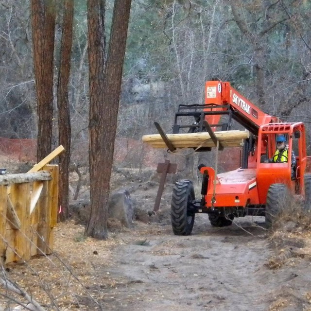 An orange construction vehicle by a partially constructed wooden bridge.