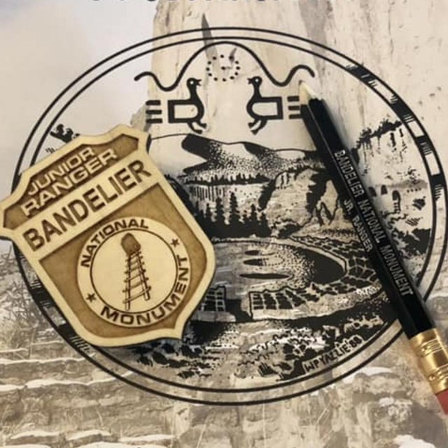 A Bandelier junior ranger badge and a green pencil sitting on a Bandeler junior ranger book.