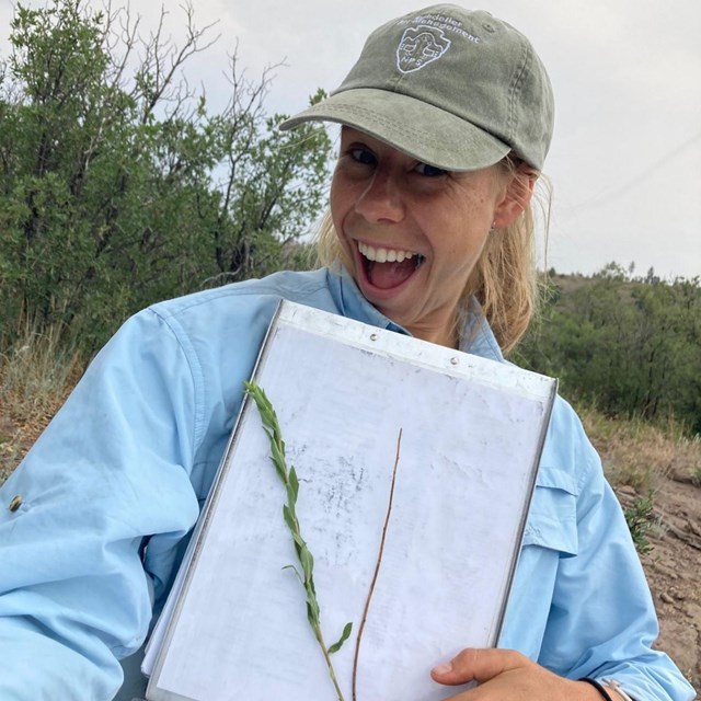 A smiling woman holding a report in her hand. 