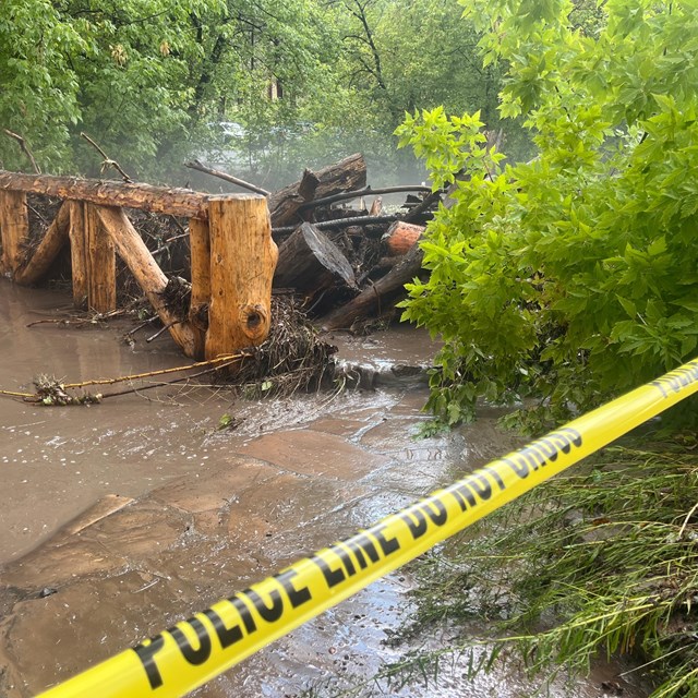 A wooden pedestrian bridge covered in rushing water.