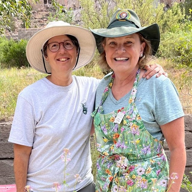 Two women standing beside each other in a garden.