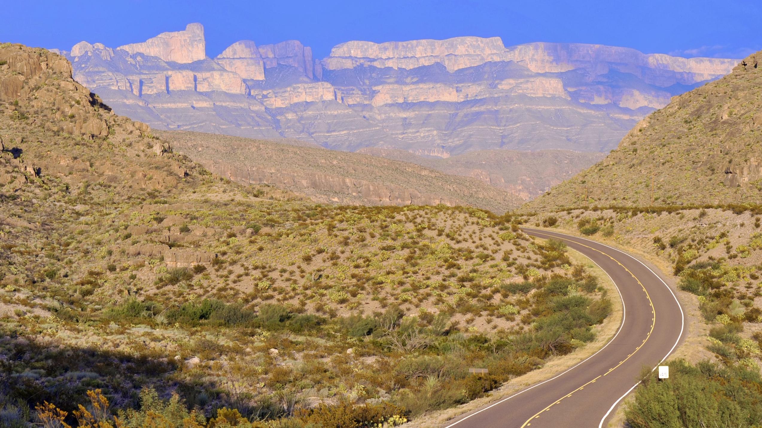 A paved scenic drive winds its way through rugged desert landscapes.