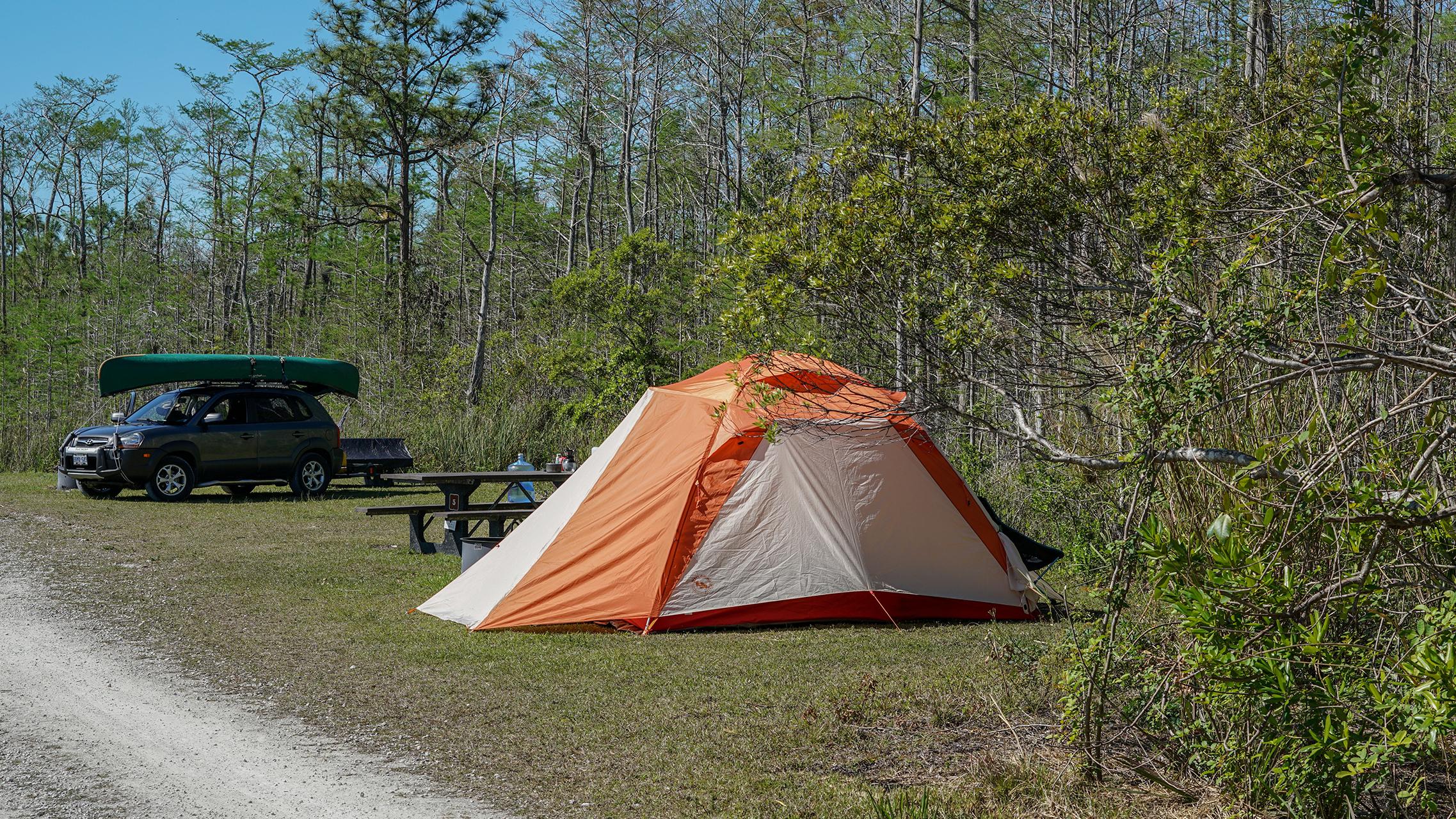 A tent in front of a car with a canoe on top
