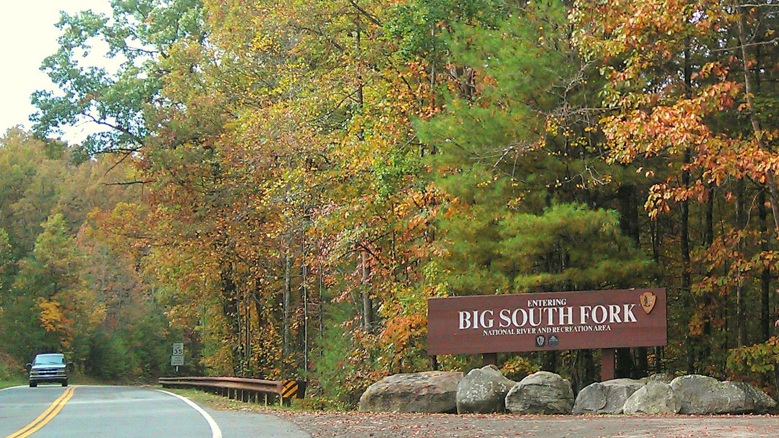 Park sign on the side with a vehicle driving on the road 