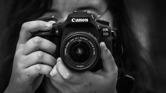 black and white photo of a person pointing their camera at the viewer.