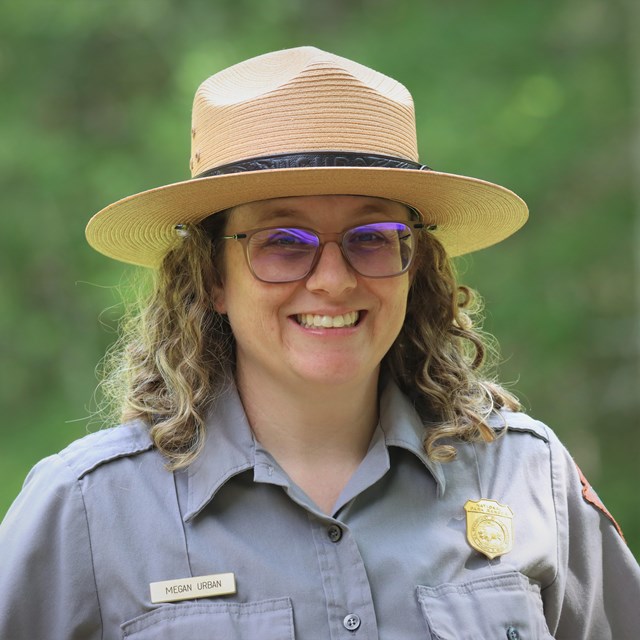 Photo of Ranger Megan smiling as she wears a flat hat.