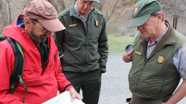 A group of park rangers looking at a document together outside