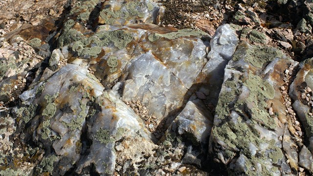 Image of a quartz rock with glittering segments of white, grey, and brown
