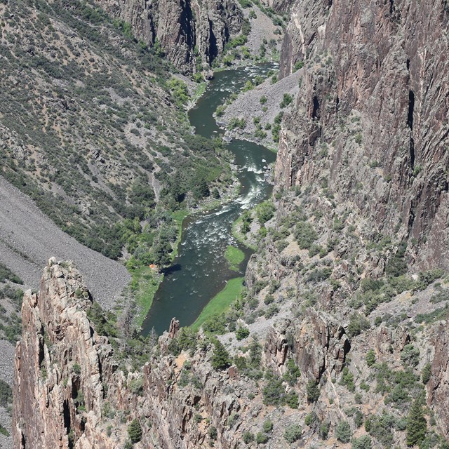 Image of a view looking down at spires next to a canyon wall and a river