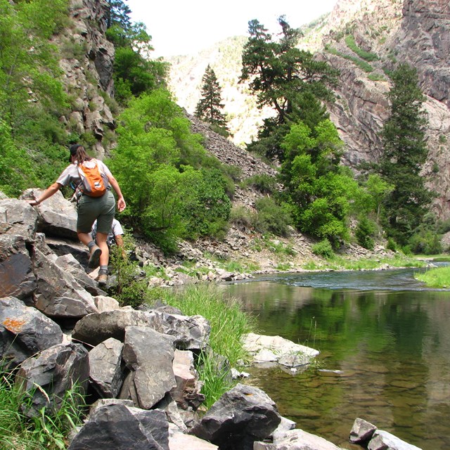 Hikers pick their way across a boulder field along Gunnison River