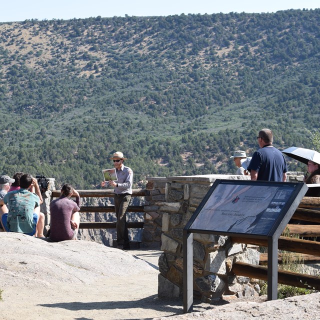 A park ranger standing at an overlook in front of a group.