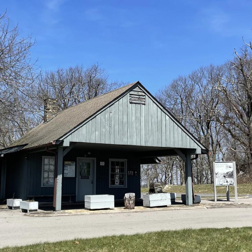 Small gray building with front porch overhang casting shadow on front of building