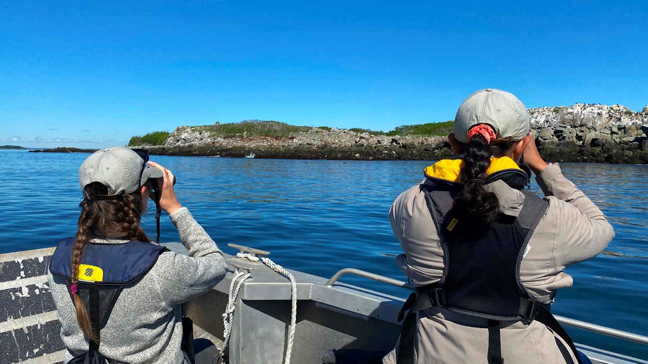 two people looking through binoculars from a landing craft.