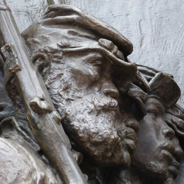 Bronze bas-relief sculpture focused on the faces of four African American soldiers