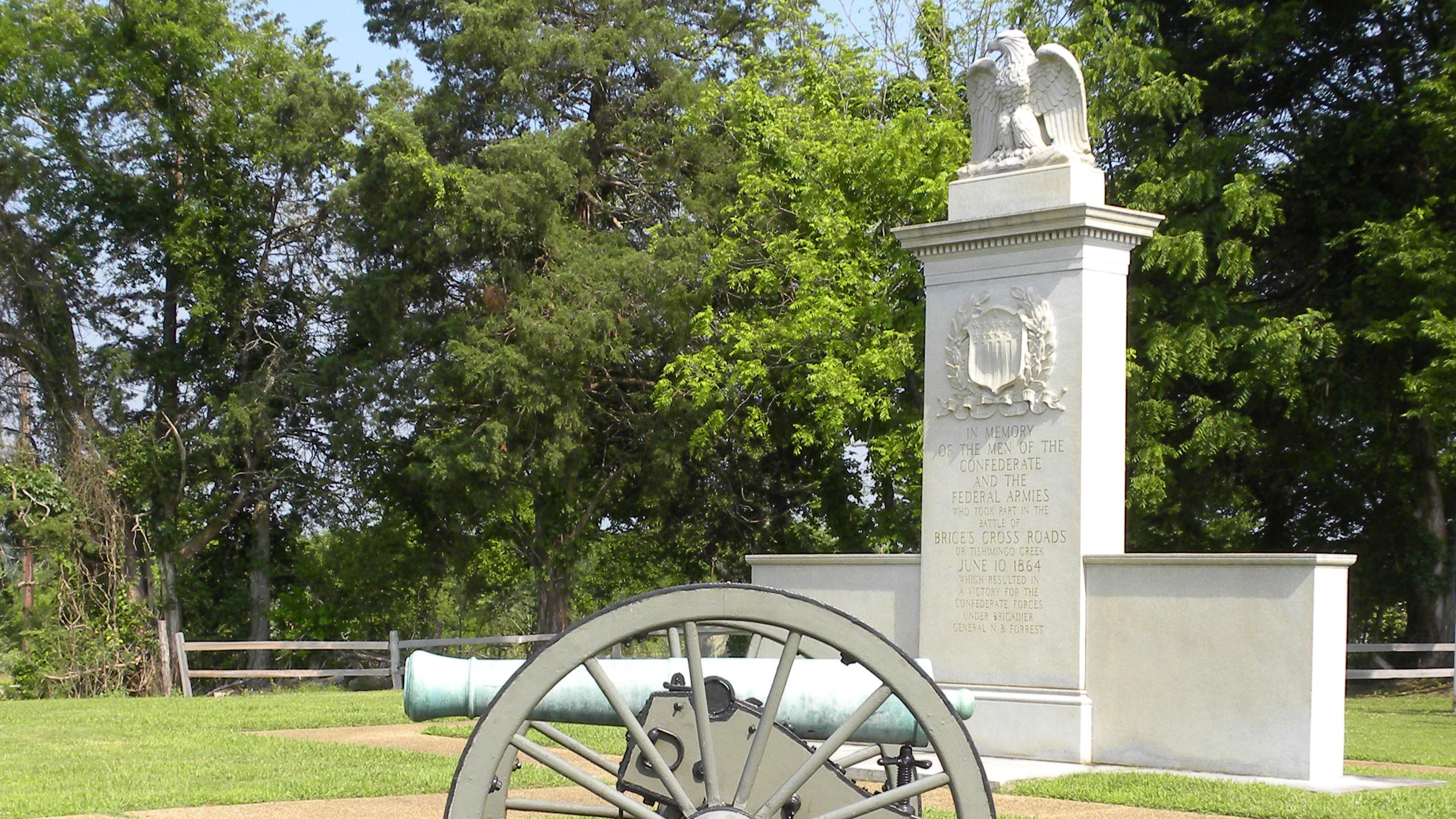Photo of Brices Cross Roads Battlefield Monument with a civil war cannon placed in front.