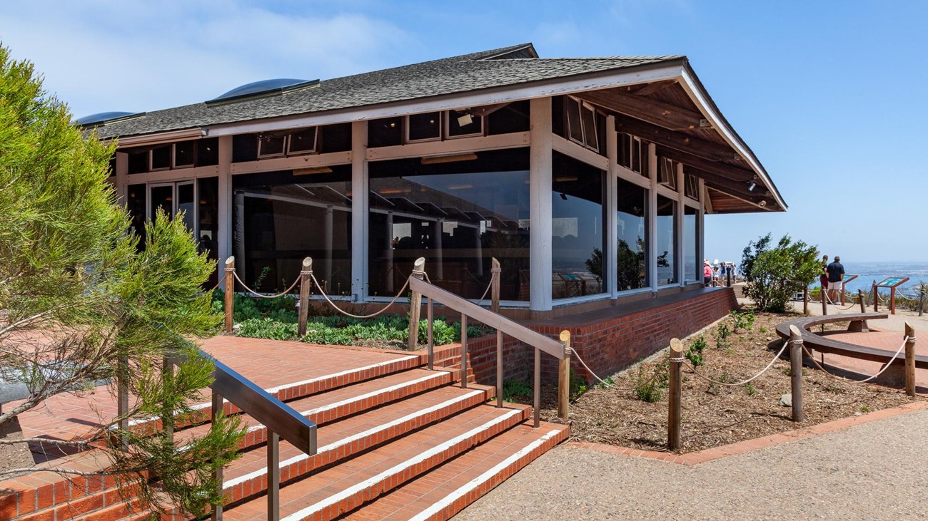 Visitor Center, featuring large windows, a slanted roof, and steps leading up to the entrance.