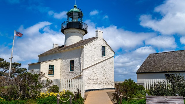 A photo of the Old Point Light House. Two buildings. One with a lighthouse tower.