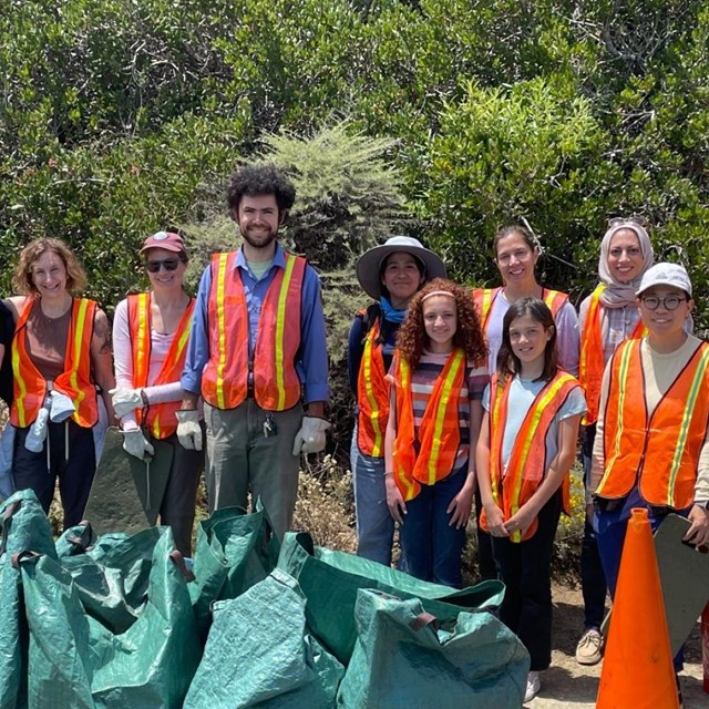 A group of volunteers from mixed age, gender, and backgrounds are smiling at the camera.