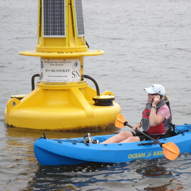 A kayaker in front of a NOAA interpretive buoy on the trail