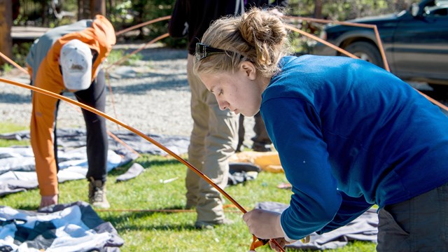 A woman breaks down a tent